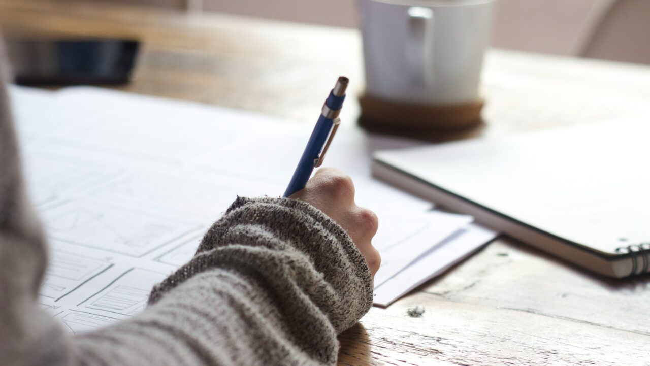 hand holding pen on paper