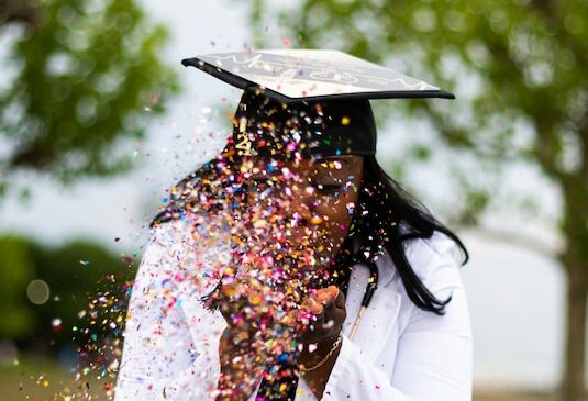 someone blowing confetti with a graduation cap